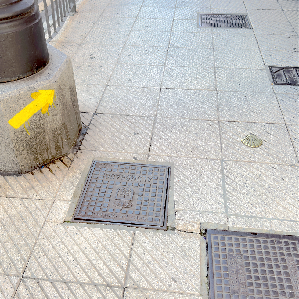 A metal shell embedded in a pavement alongside a yellow arrow pointing forward