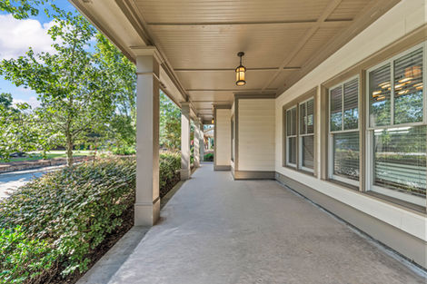 Long covered porch with columns and lantern lighting alongside the home