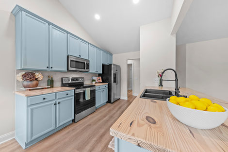 Kitchen with butcher block counters, black faucet and stainless appliances