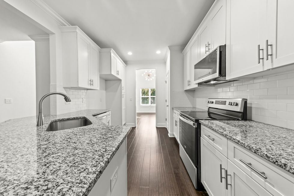 Kitchen looking down the galley with island and stainless appliances