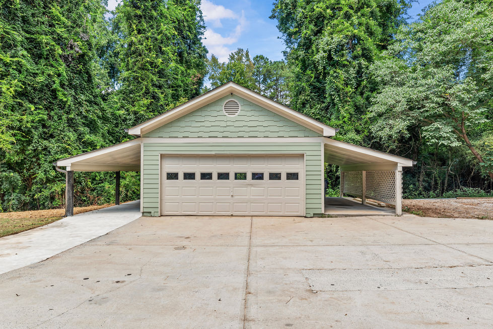 Detached garage with attached carport and wide concrete driveway