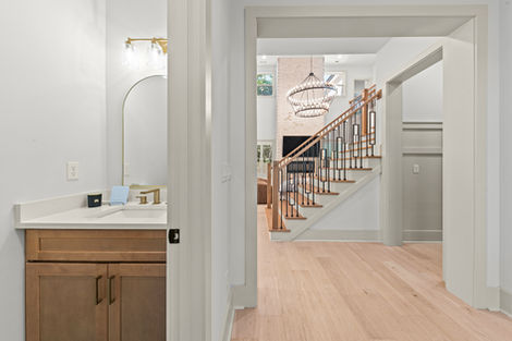 Powder room vanity with arched mirror off the entry hall