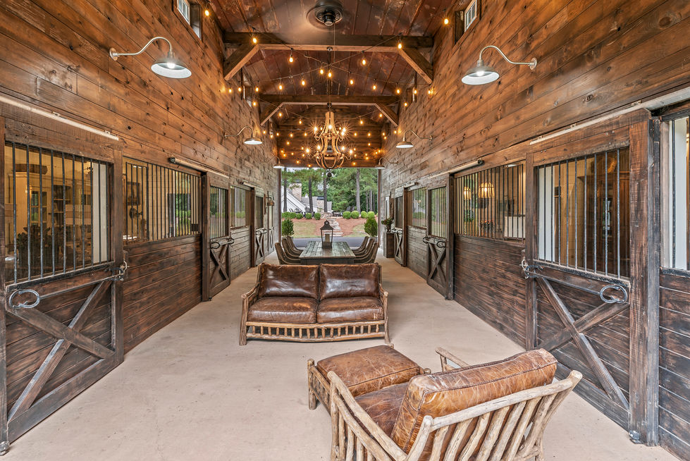 Horse barn interior with wood stalls, center aisle seating and iron chandelier
