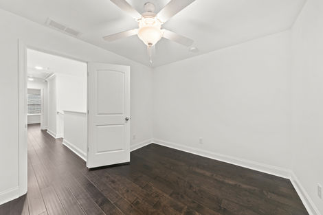 Bedroom with ceiling fan and doorway to the hall
