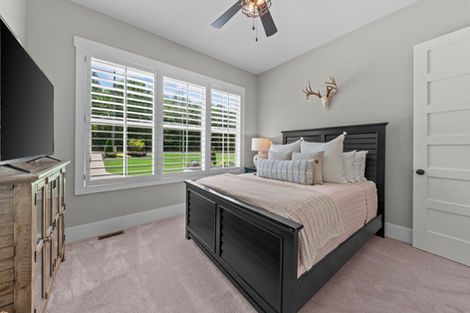 Bedroom with dark wood bed, plantation shutters and mounted television
