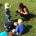 children with their teacher in a green grass field
