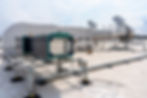 Rooftop HVAC system with large ductwork and metal supports against a partly cloudy sky. Wires and boxes scattered on the concrete surface.