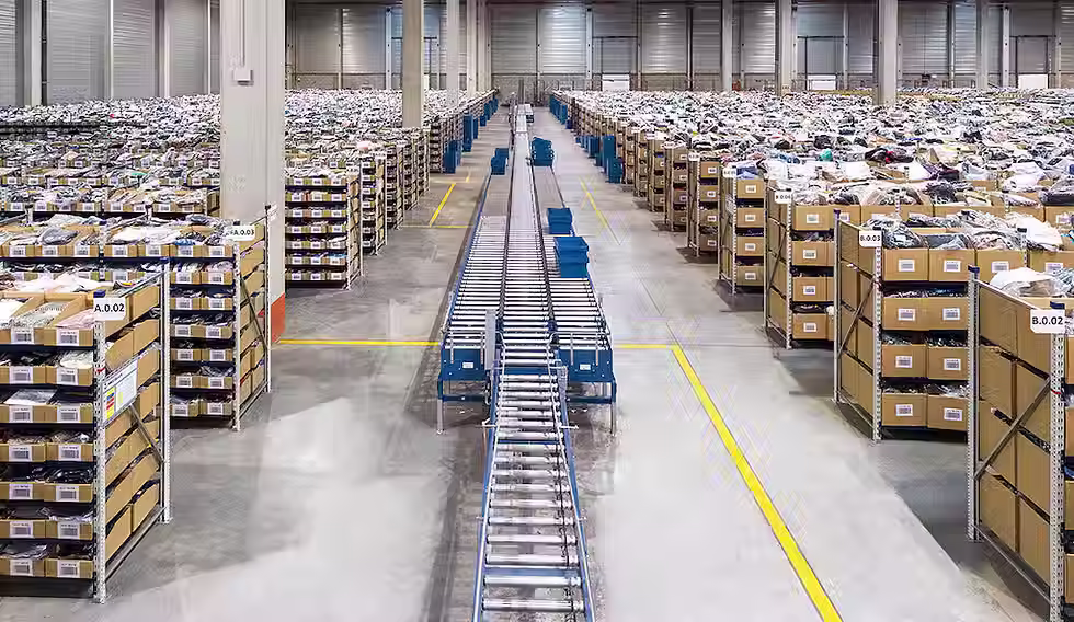 A large fulfillment warehouse with shelves lining both sides of the warehouse and a conveyor belt in the middle.