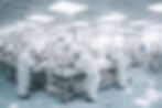 Scientists in white protective suits work in a bright, sterile lab with advanced equipment, reflecting a focused and clean environment.