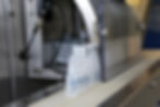 Clear plastic bottles on a conveyor belt in an industrial setting, with metallic machinery and cables in the background.