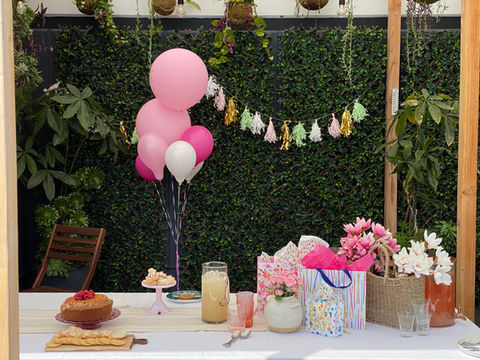 Pink balloons, gifts, and cake at an outdoor party