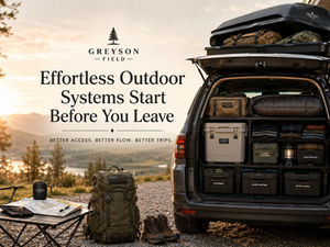 Wide hero image showing an organized vehicle packing system before an outdoor trip, with open cargo storage, labeled gear bins, rooftop cargo box, backpack, boots, map table, and mountain sunrise scenery.