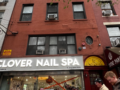 Street‑level view of the red‑brick building at 210 West 14th Street, with a nail salon and sushi restaurant on the ground floor, showing the façade where Marcel Duchamp once rented the top‑floor studio.
