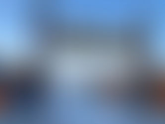 Colorful tents on a snowy field with a wooden arch bearing Chinese text. People walk nearby. Clear sky and trees in the background.