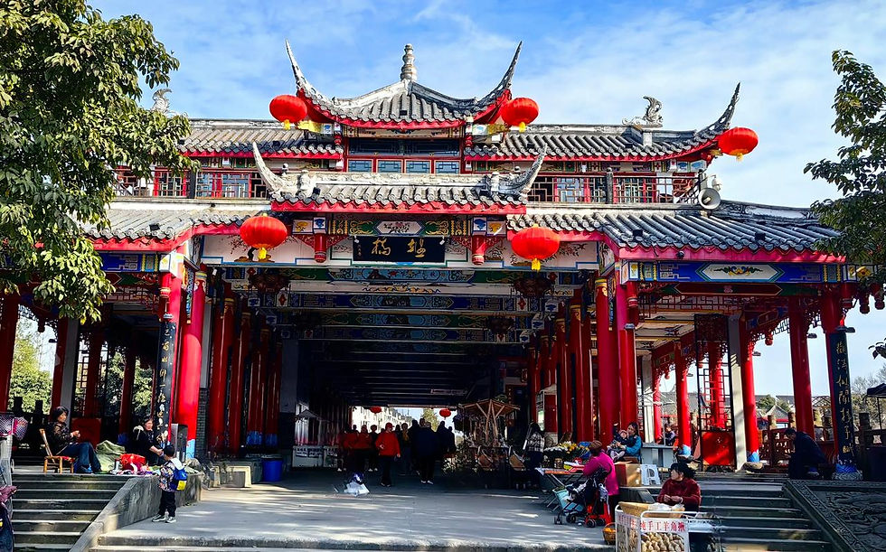 Traditional Chinese building with red lanterns, people milling around. Blue sky in background, lively and colorful scene with intricate details.