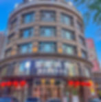 Round multi-story building with arched windows, red lanterns, and Chinese text on the facade. Clear blue sky and part of a billboard visible.
