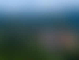 Aerial view of a waterfall cascading down lush green cliffs with misty mountains in the background. The scene is serene and majestic.