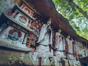Ancient rock carvings with serene Buddha statues and vibrant murals in a lush, green forest setting, conveying peace and timelessness.