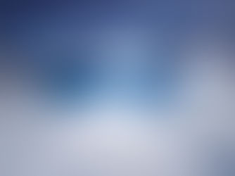 Snowy mountains surround a blue crater lake under a cloudy sky. The scene feels cold and serene with mist rising from the lake.