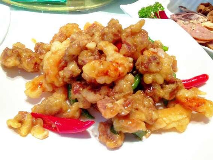 Close-up of a plate with crispy fried shrimp and colorful red and green peppers. White background, yellowish-gold tones, appetizing vibe.