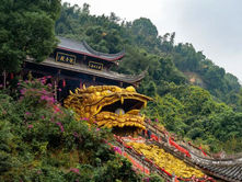 Golden dragon head sculpture on temple steps, adorned with red banners. Lush green forest surrounds, creating a mystical atmosphere.