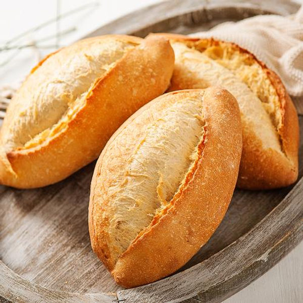 Three freshly baked crusty rolls on a wooden tray, with a beige napkin. The golden-brown texture suggests warmth and comfort.