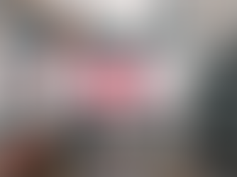 City street scene with yellow taxis and cars, busy traffic. Huge billboard with red Chinese text. Tall buildings surround the overcast setting.