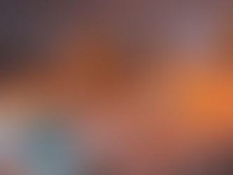 Snow-covered cityscape at night with brightly lit buildings and glowing orange lights, creating a warm contrast against the snowy scene.