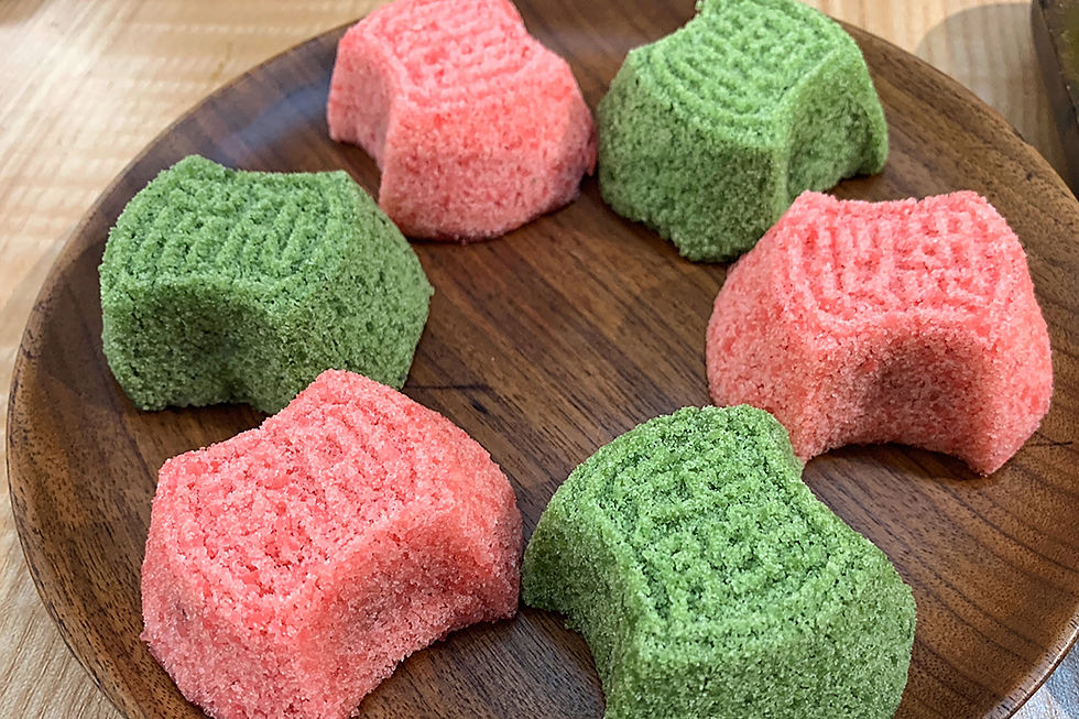 Pink and green sugar cakes with stamped designs on a wooden plate, set on a wooden table, creating a bright and appetizing look.