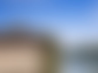 Historic Chinese building by a riverside, with a small boat on the water. Green trees and blue sky create a serene atmosphere.