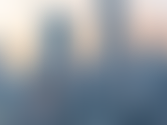 Red cable car traverses against a city skyline at sunset, with tall skyscrapers and visible text on buildings in the background.