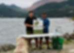The AHOI Green Team, Daniel Laing (left) and Matt Smith (right) posing with the Conservation Corps NL sign at a beach cleanup in Woody Point, NL.