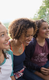 Mother and pre-teen or teen children on a hammock