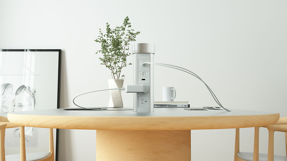 Modern table with power outlet tower, plant, mug, and "GRAPHIC DESIGNERS" book. Art leaning against white wall. Minimalist decor.