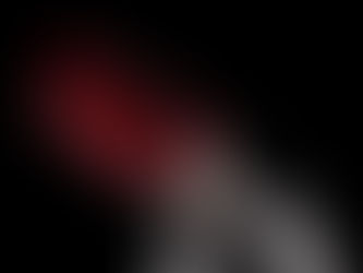 Close-up of a red-lidded lipstick tube against a black background, showcasing sleek metallic design and vibrant red cap.
