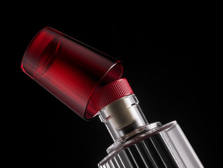 Close-up of a red-lidded lipstick tube against a black background, showcasing sleek metallic design and vibrant red cap.