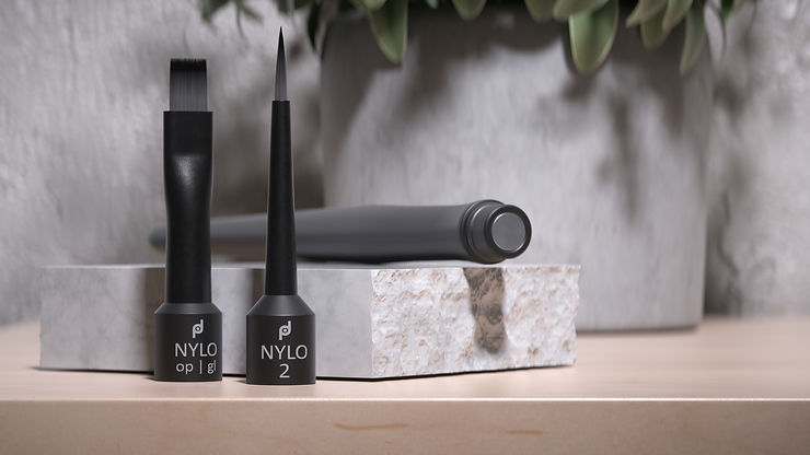 Black eyeliner brushes labeled "NYLO op|gl" and "NYLO 2" on a marble block. Gray wall and plants in the blurred background. Sleek and modern.