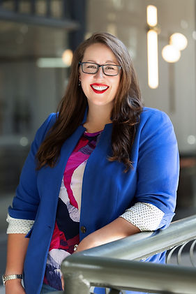 Sumiko Martinez, the company founder, smiles at the camera while resting her arm on a railing. She is wearing a blue jacket and glasses.
