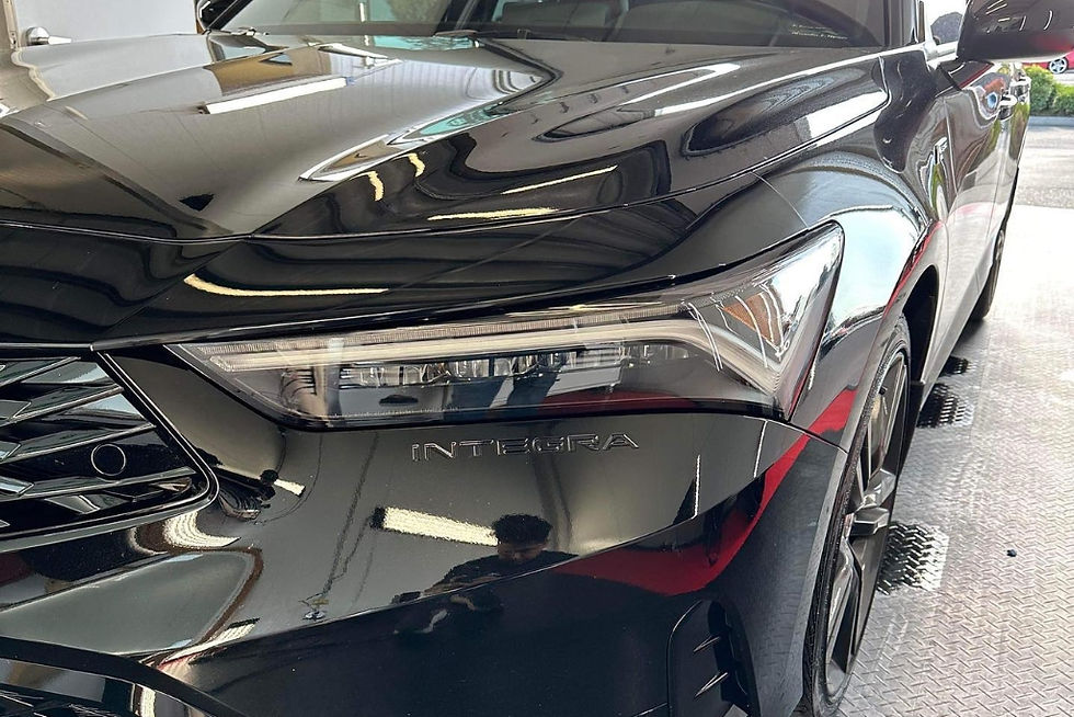 A person points to multiple scratches and scuffs on the lower bumper of an orange car, emphasizing areas where Paint Protection Film would not be effective in concealing deep paint damage.