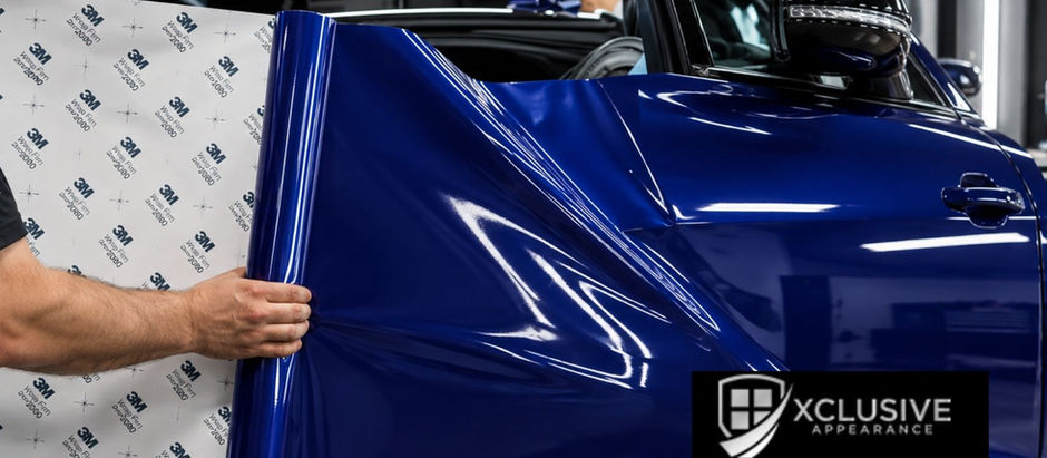 Technician applying a glossy blue vinyl car wrap to a vehicle at Xclusive Appearance.