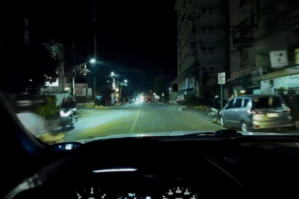 A nighttime driving scene viewed from inside a car, showing a clear view of the road and surroundings through a window with ceramic tint. The scene highlights how ceramic window tint enhances visibility while providing UV and heat protection.