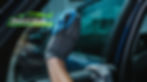 A gloved hand cleaning a car window using a blue microfiber cloth, with a logo in the top left corner that reads "Advanced Window Tint & Paint Protection" in white and green text, featuring a green car silhouette.