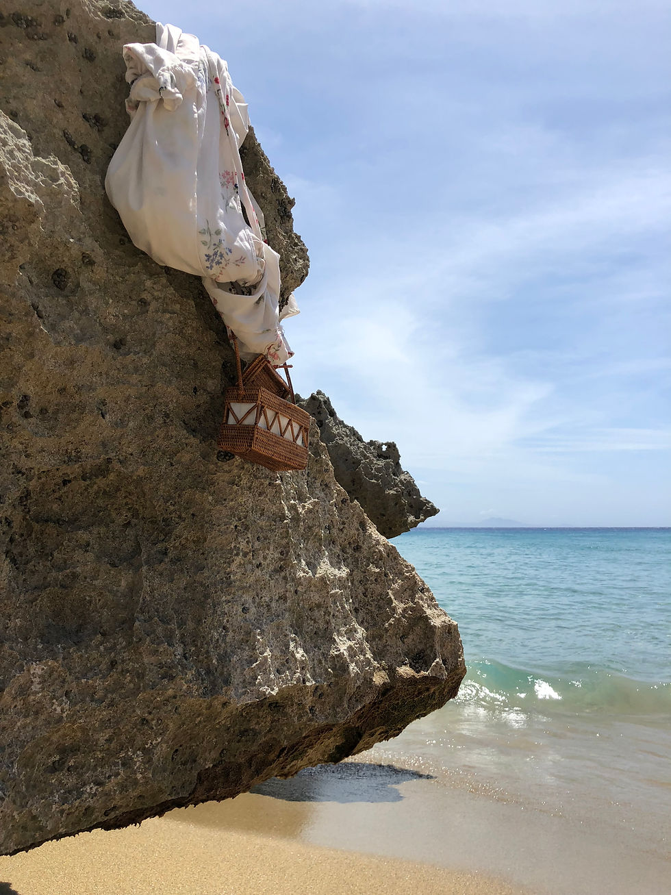 Beach Photo of Sheridans bag and swimsuit cover up or dress hanging off a rock with the blue ocean and open sky in the background What Sheridan Said is a Narrative Drama Series following the Chaotic Life of Writer and Business Woman Sheridan Guerrette
