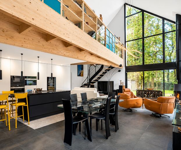 Pièce de vie de la maison rénovée, avec de grandes baies vitrées créant une continuité entre intérieur et extérieur.