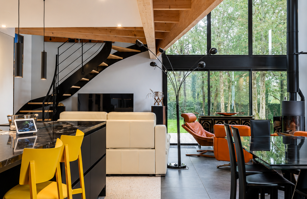 Pièce de vie de la maison rénovée, avec de grandes baies vitrées créant une continuité entre intérieur et extérieur.