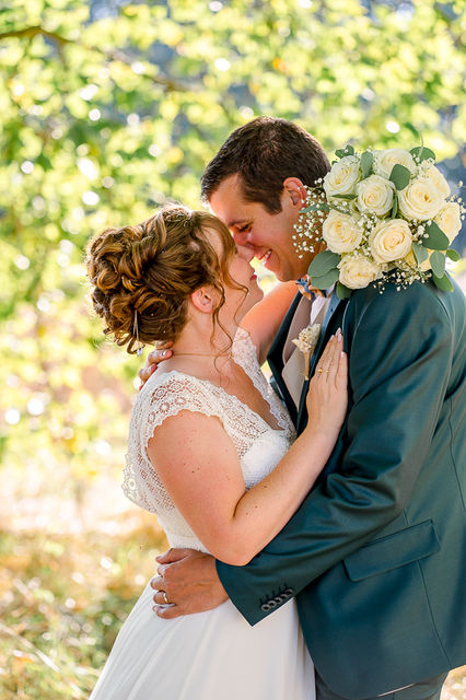 Jeune couple s'embrassant, bouquet de roses blanches, mariage en plein air, amour.