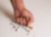 Fist of a man hitting a pile of broken cigarettes on a white table, as a sign of disapprov