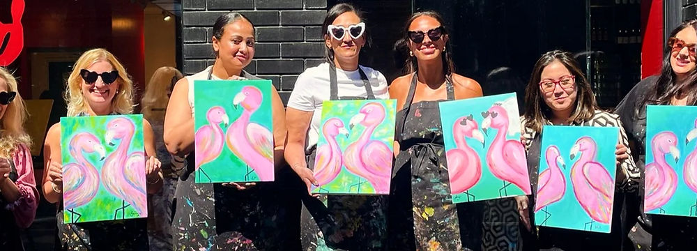 Group of friends smiling and painting colourful canvases at a sip and paint class in London