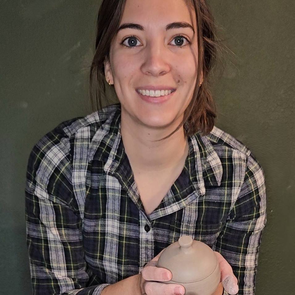 The artisan behind Miner Pottery, holding an in-progress piece