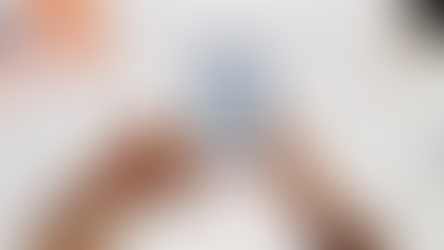 Smartphone on a tripod filming three creators in front of a brick wall, holding paint cans and a color swatch during a content shoot.